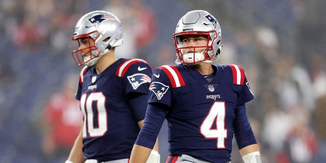 Mac Jones (10) and Bailey Zappe (4) of the New England Patriots stand on the field prior to a game against the Chicago Bears at Gillette Stadium Oct. 24, 2022 in Foxborough, Mass.