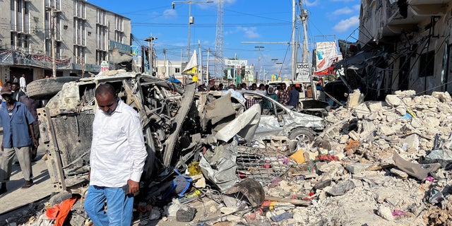 A man walks past wreckages of destroyed vehicles near the ruins of a building at the scene of an explosion along K5 street in Mogadishu, Somalia October 30, 2022. 