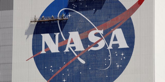 Workers on scaffolding repaint the NASA logo near the top of the Vehicle Assembly Building at the Kennedy Space Center in Cape Canaveral, Florida, May 20, 2020.
