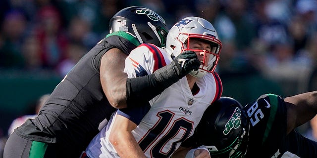 New York Jets defensive end John Franklin-Myers, left, and defensive end Carl Lawson put a late hit on New England Patriots quarterback Mac Jones, Sunday, Oct. 30, 2022.
