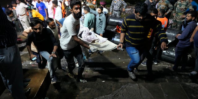 Volunteers and health workers carry a victim after a cable bridge across the Machchu river collapsed in Morbi town of western state Gujarat, India, Monday, Oct. 31, 2022.