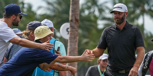 Team Captain Dustin Johnson of 4 Aces GC fist bumps fans between the ninth and tenth holes during the team championship stroke-play round of the LIV Golf Invitational - Miami at Trump National Doral Miami on October 30, 2022 in Doral, Florida. 