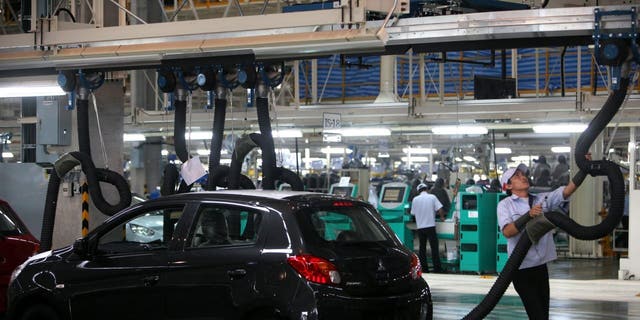 FILE - A Mitsubishi Motors Corp. worker operates equipment on the production line of the Mirage vehicle at the company's plant in Laem Chabang, Thailand.
