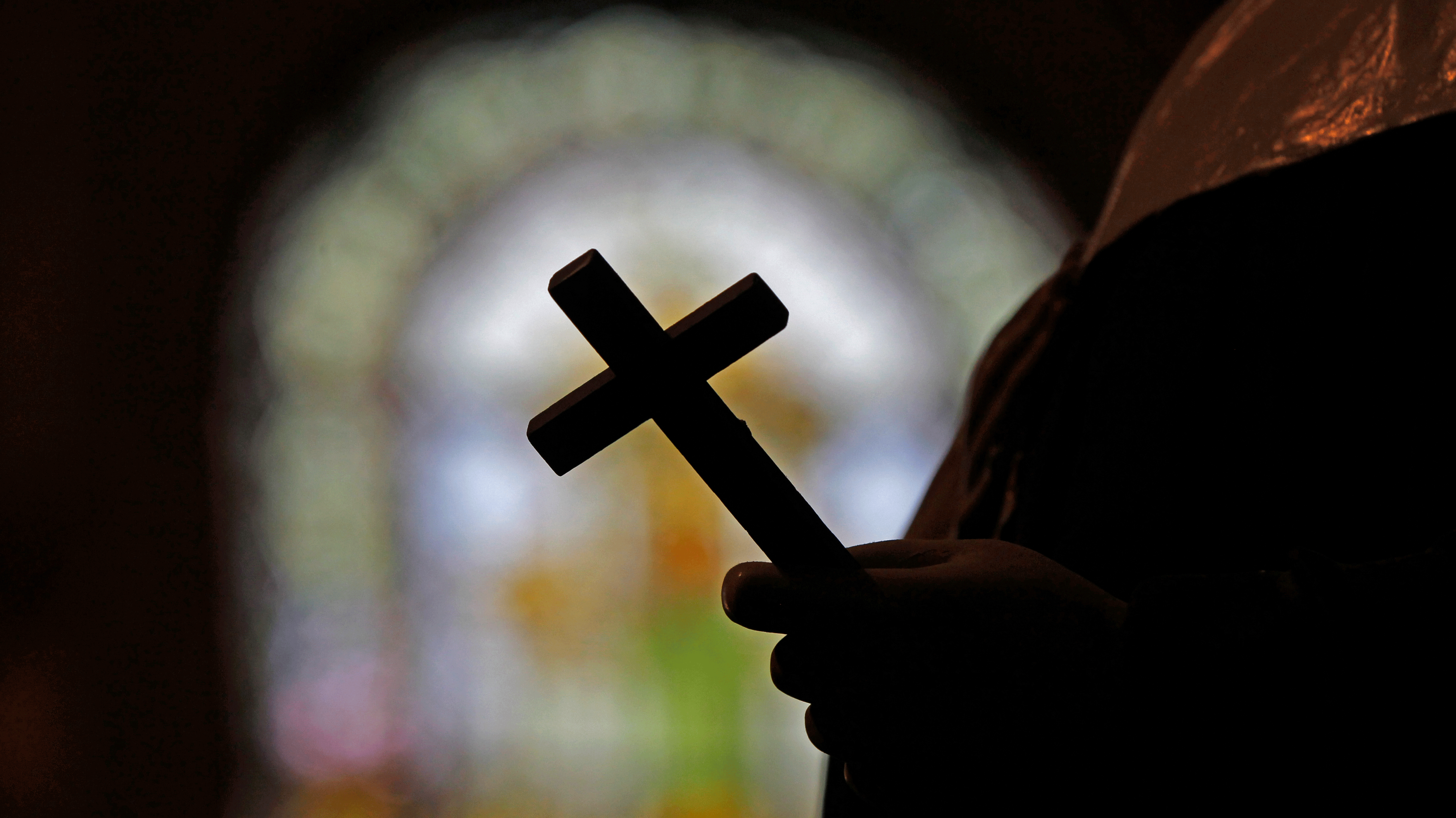 File photo shows a silhouette of a crucifix and a stained glass window inside a Catholic Church in New Orleans. 