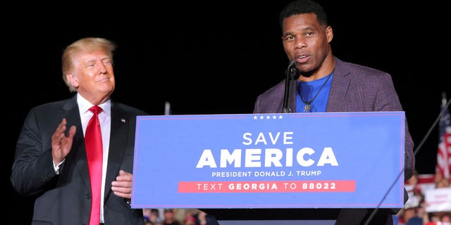 Former college football star and current senatorial candidate Herschel Walker speaks at a rally, as former U.S. President Donald Trump applauds, in Perry, Georgia, U.S. September 25, 2021.