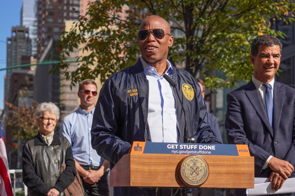 Mayor Eric Adams in sunglasses speaks behind a podium