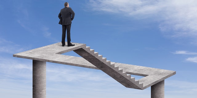 Rearview of businessman standing on a floating staircase with cloudy sky background. This digitally generated image points to the metaphysical.
