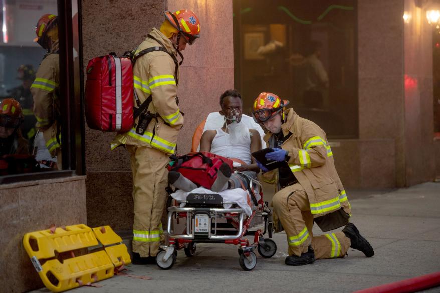 Man in a stretcher is aided by firefighters