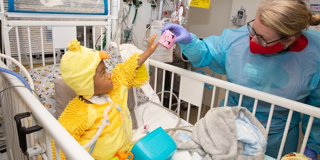 A child in the hospital dressed in a costume interacts with a nurse during a Halloween party thrown by Spirit of Children.