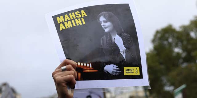 A protester shows a portrait of Mahsa Amini during a demonstration to support Iranian protesters standing up to their leadership over the death of a young woman in police custody, Sunday, Oct. 2, 2022 in Paris. 