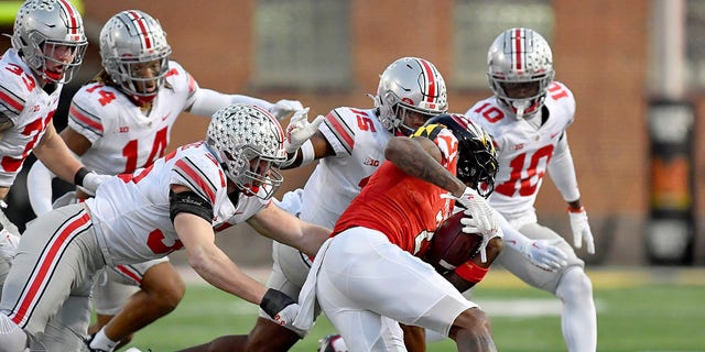 Ohio State defensive end Jack Sawyer (33), safety Ronnie Hickman (14), linebacker Tommy Eichenberg (35), safety Tanner McCalister (15) and cornerback Denzel Burke (10) converge on Maryland wide receiver Jacob Copeland (2) during a game Nov. 19, 2022, at Capital One Field at Maryland Stadium in College Park, Md.