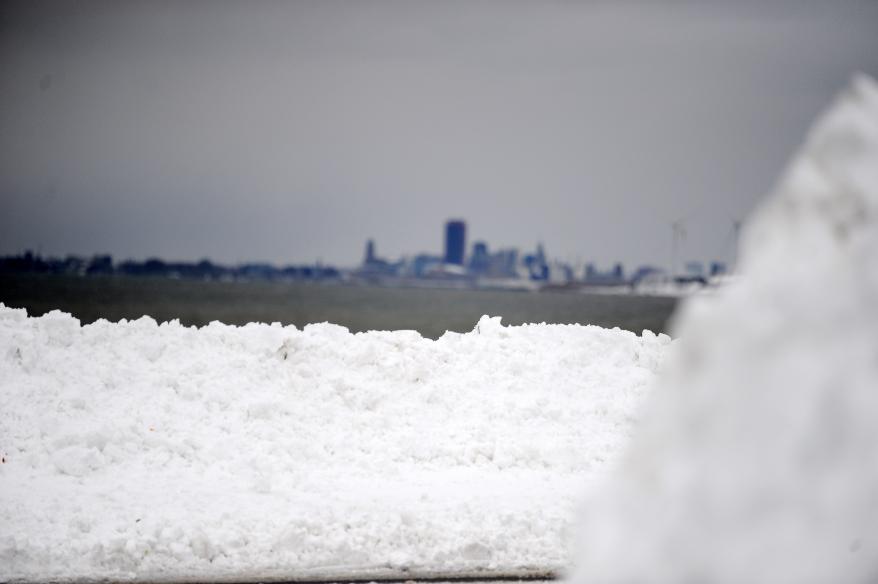 A mound of snow with the Buffalo skyline behind it.