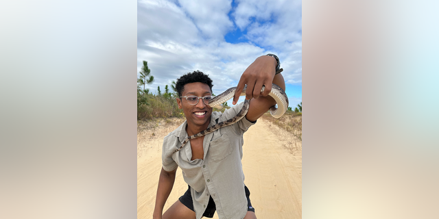 Christian Cave, a Kennesaw State University environmental science student in Georgia, poses for a photo with the snake he'd long been hoping to find.