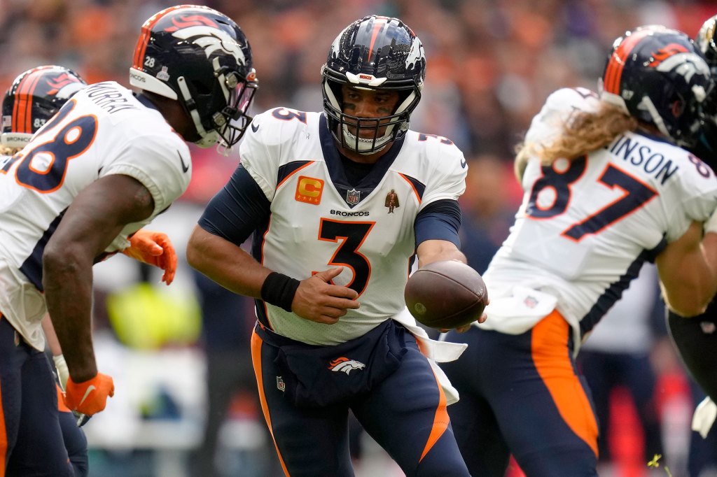 Denver Broncos quarterback Russell Wilson (3), centre, hands the ball over